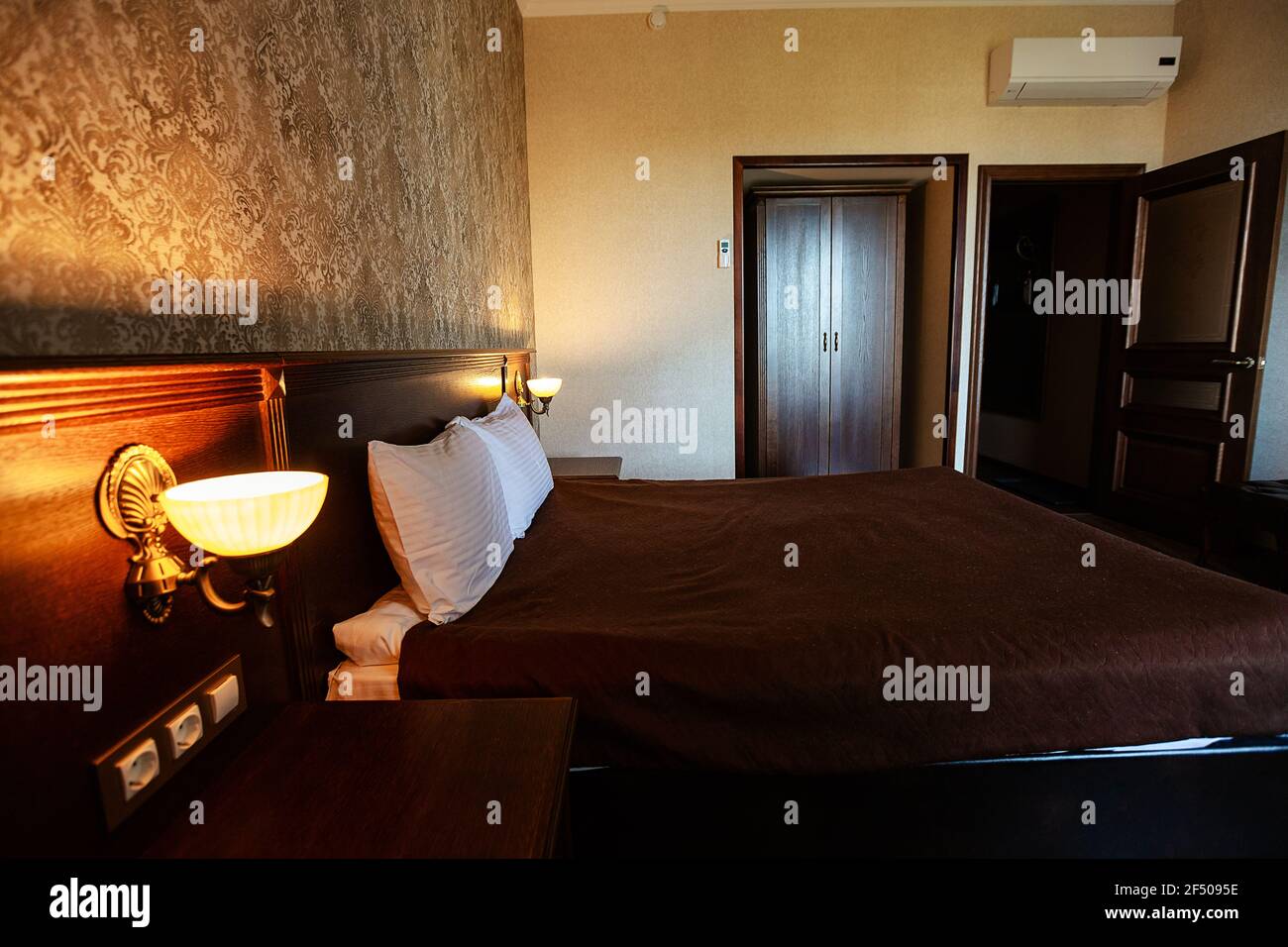 cama y lámpara en el hotel. interior acogedor y sencillo en el dormitorio. una habitación en colores oscuros para que los huéspedes se relajen Foto de stock