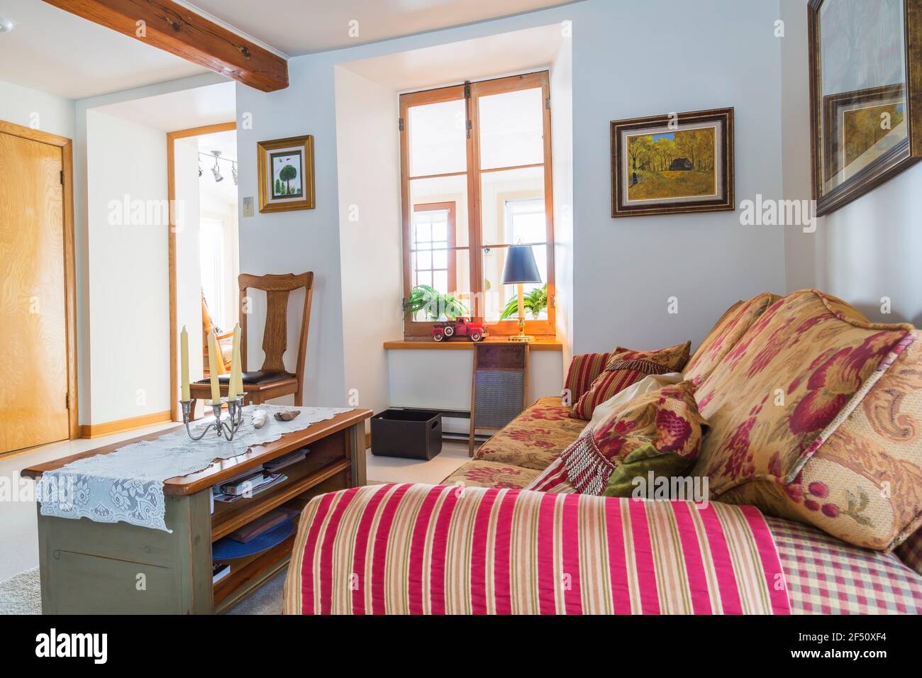 Sofá-cama de cuadros rojo, beige, gris con asientos floridos y cojines de  respaldo, mesa de café de madera y silla alta con asiento remachado de  cuero negro Fotografía de stock - Alamy