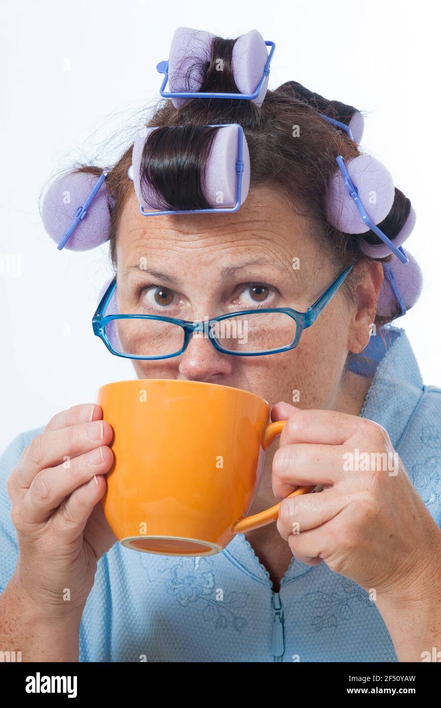 Disparo vertical de una mujer madura con curlers de cabello bebiendo café. Esta es una imagen revisada. Foto de stock