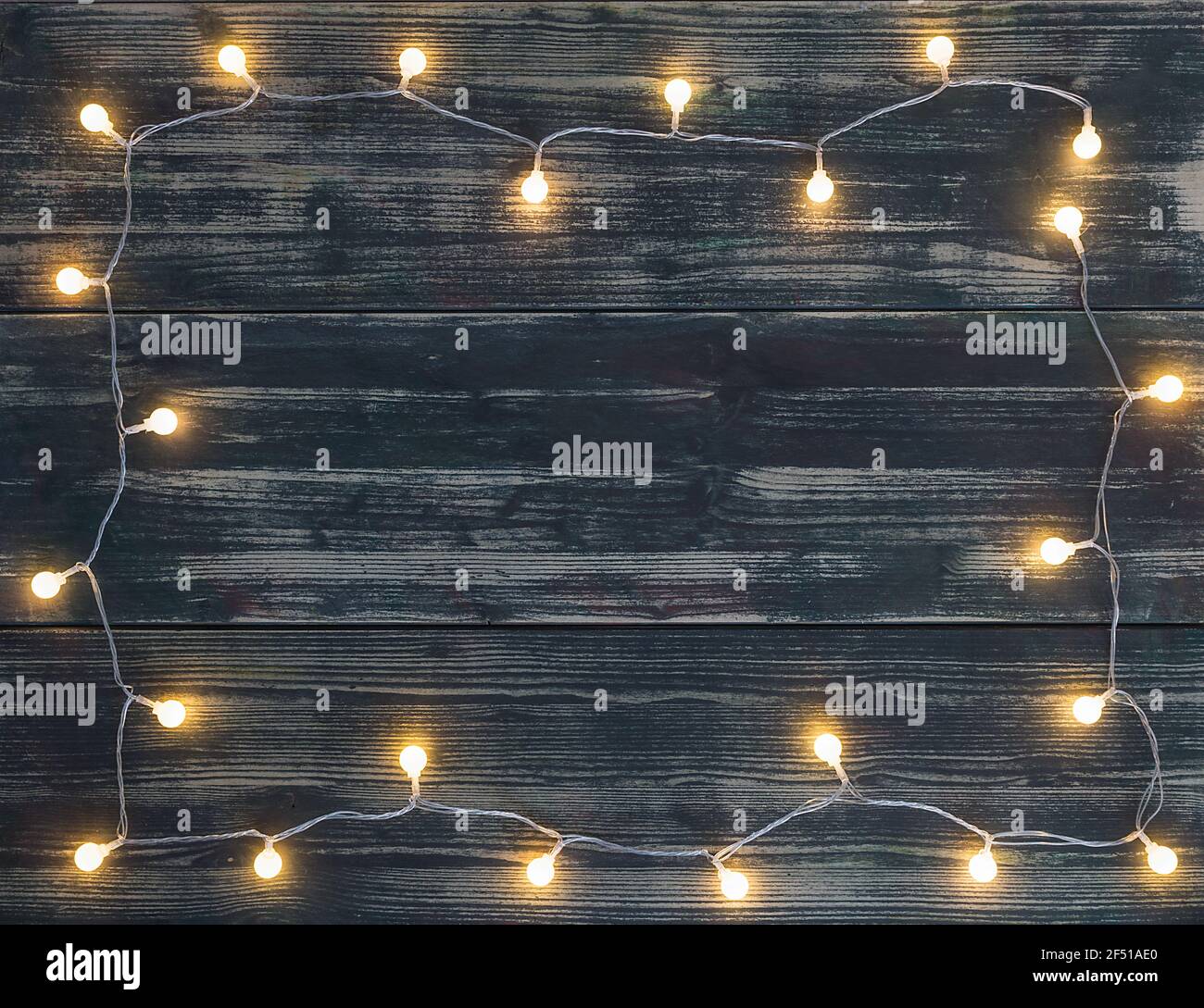 guirnalda de luces de navidad redondas con colores cálidos la forma de un  marco sobre fondo oscuro de madera tablas Fotografía de stock - Alamy