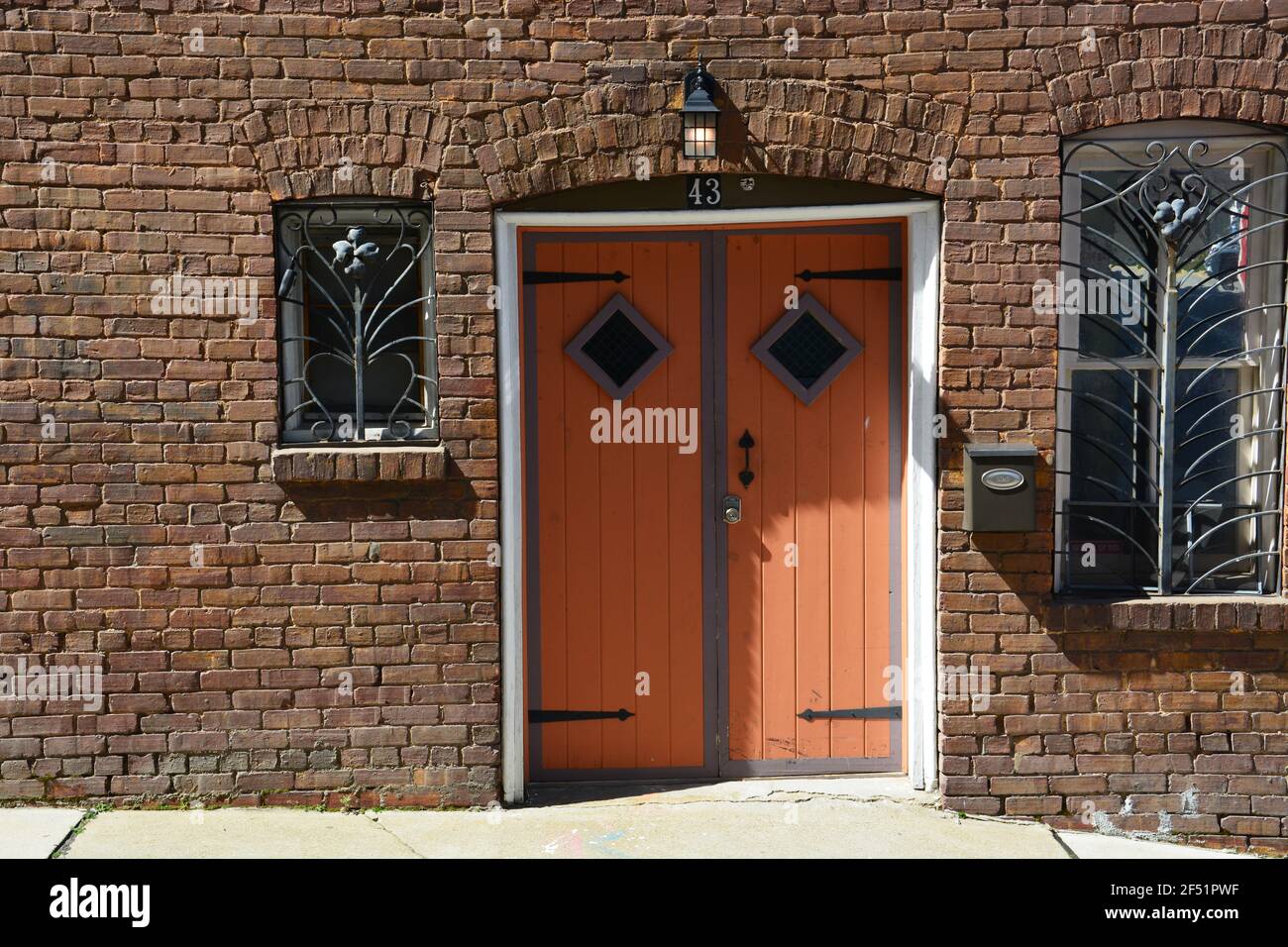 Una puerta doble con barras de burglar de hierro ornamentado en las ventanas de un callejón en el distrito histórico de Asheville, Carolina del Norte. Foto de stock