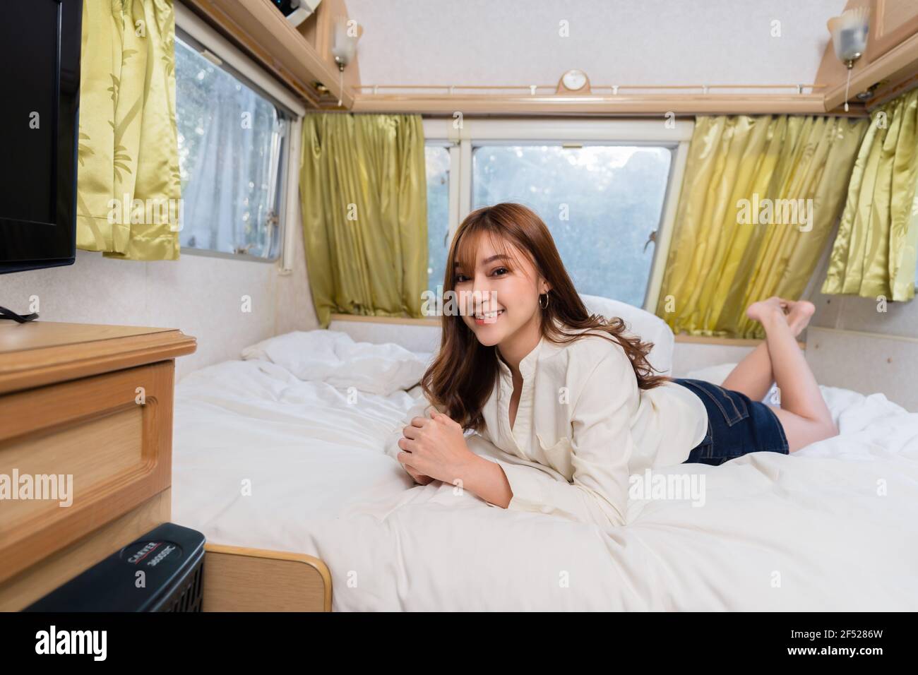 Feliz mujer joven en la cama de un autocaravana autocaravana Foto de stock