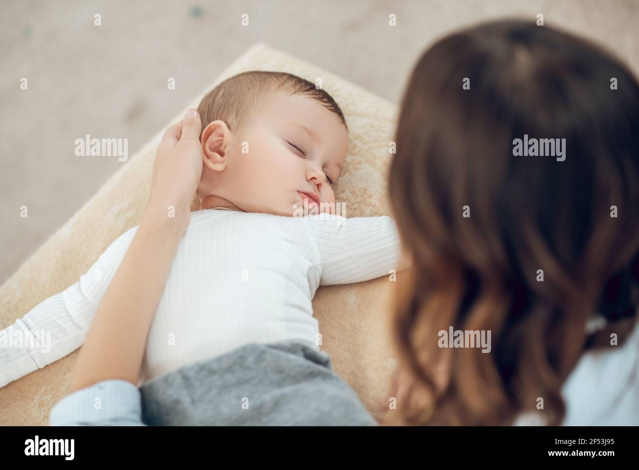 Mamá tocando la cabeza del niño dormido Foto de stock