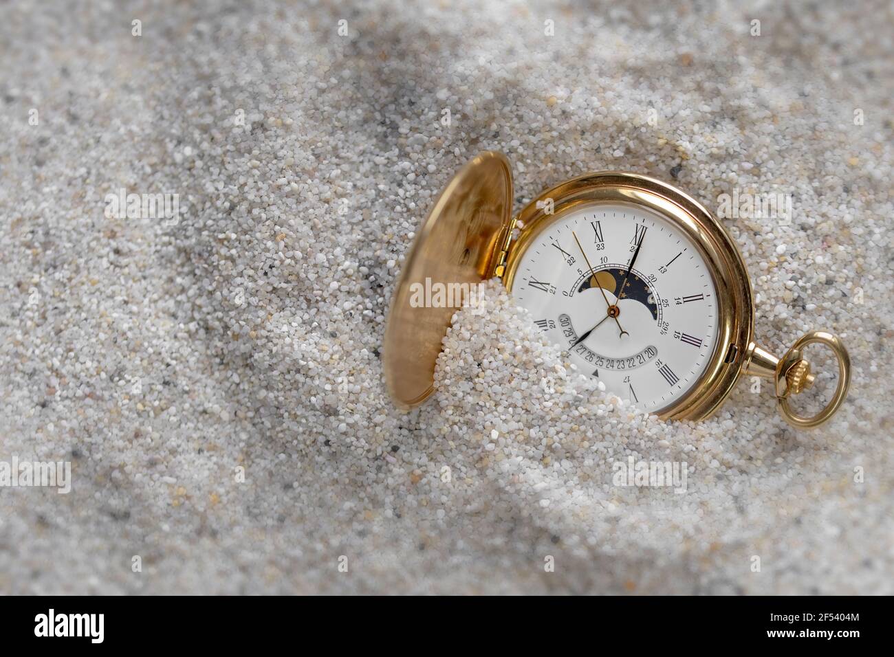 Un antiguo reloj de oro en la arena a la luz del día. Foto de stock
