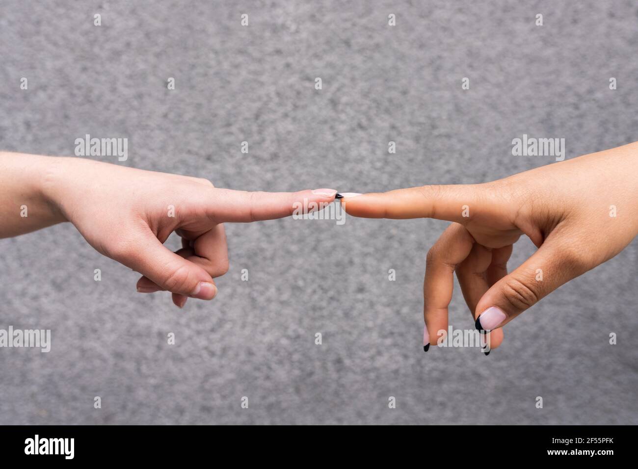 Manos de dos mujeres jóvenes que tocan con los dedos índice Foto de stock