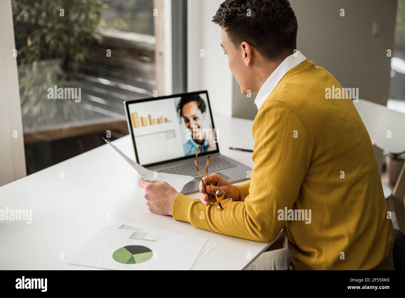 Hombre de negocios que asiste a una videoconferencia a través de un ordenador portátil mientras está sentado en el escritorio en la oficina doméstica Foto de stock