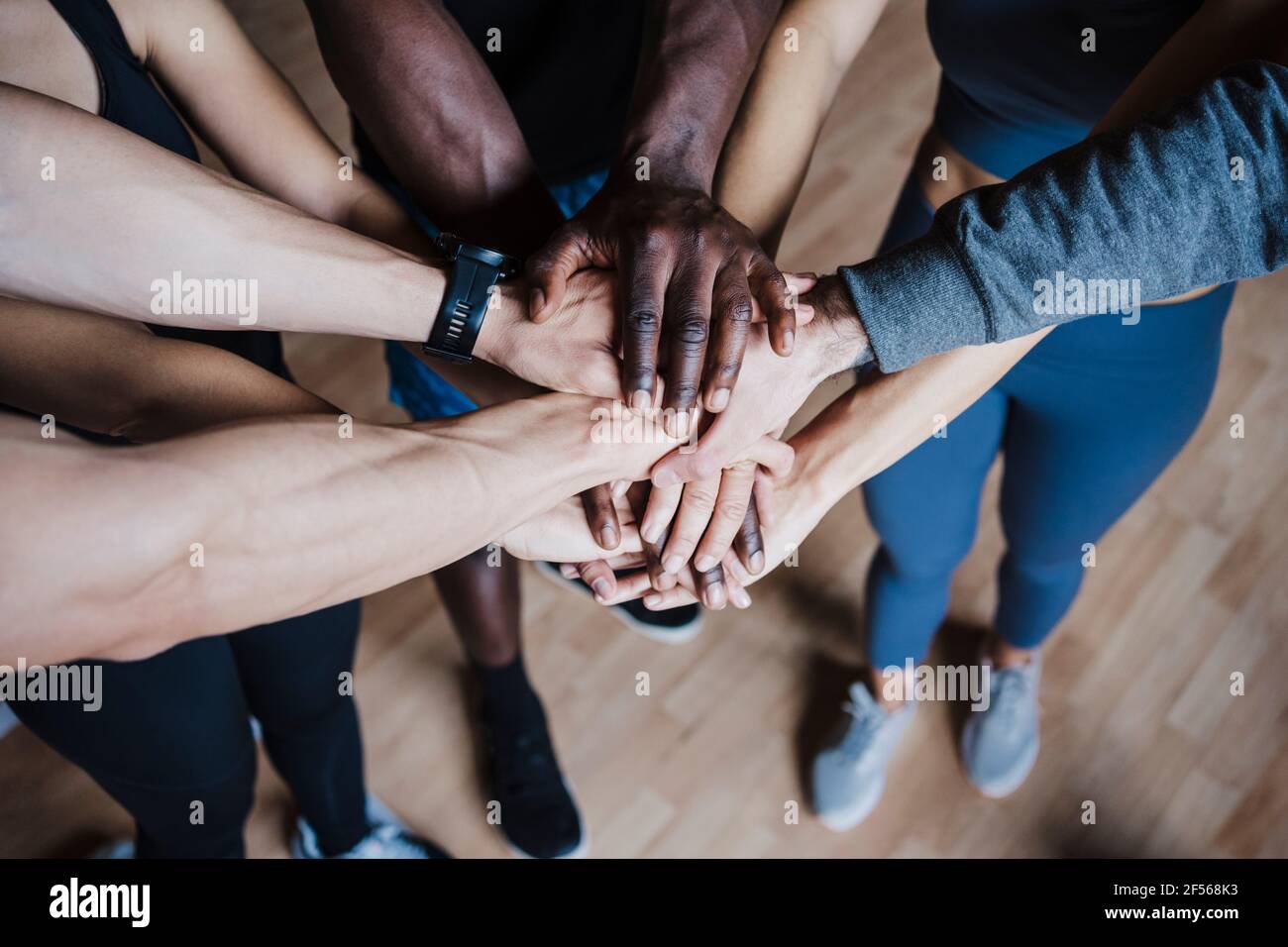 Grupo multiétnico de amigos que se acurrudan mientras están de pie en el gimnasio Foto de stock