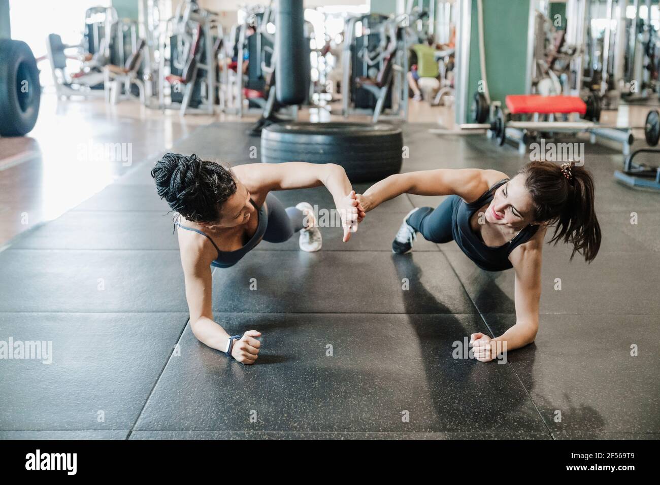 Mujeres atletas amigas dando alto-cinco mientras que hacen plancha en salud estudio Foto de stock