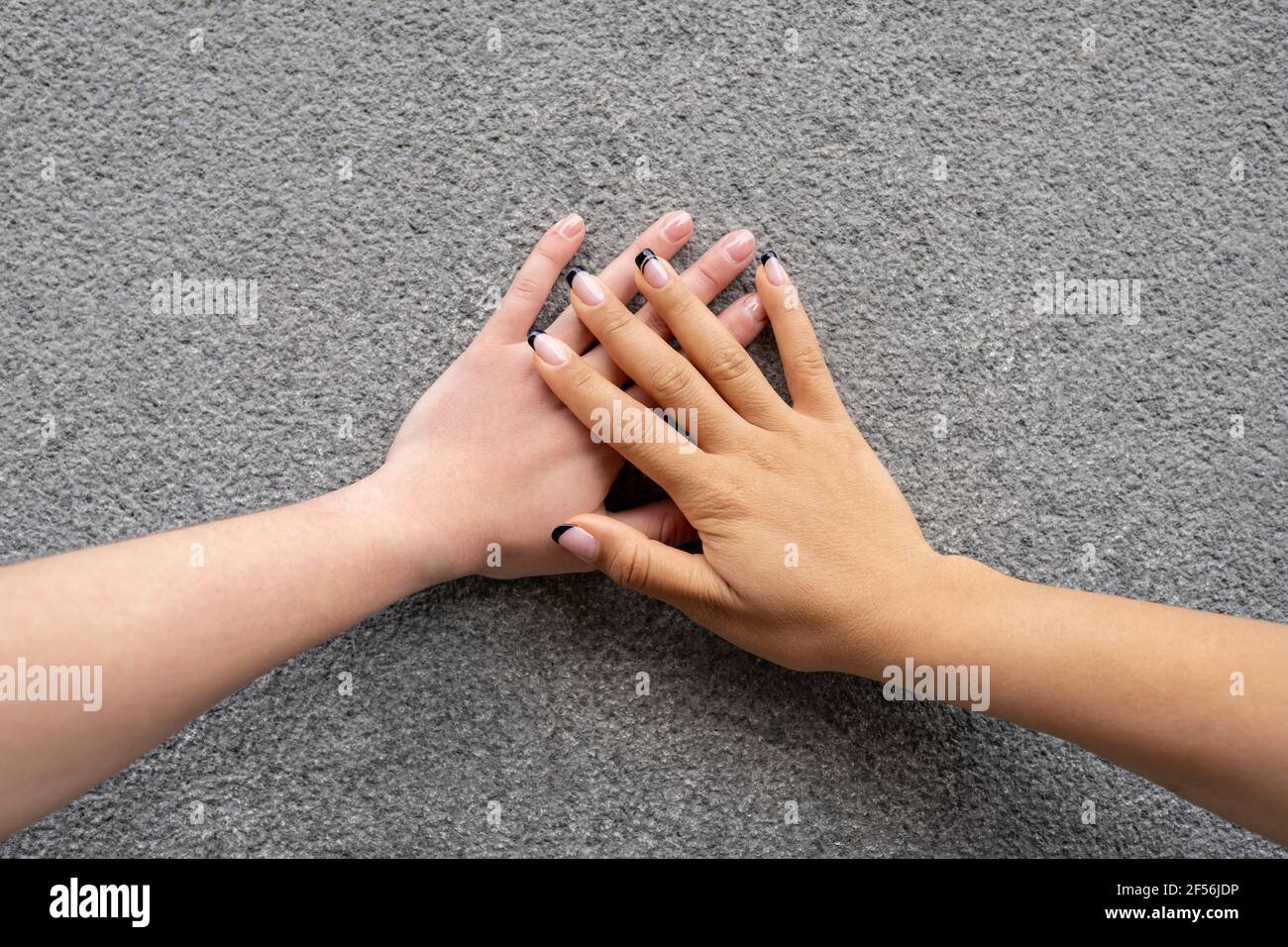 Manos de dos mujeres jóvenes tocándose unas a otras Foto de stock