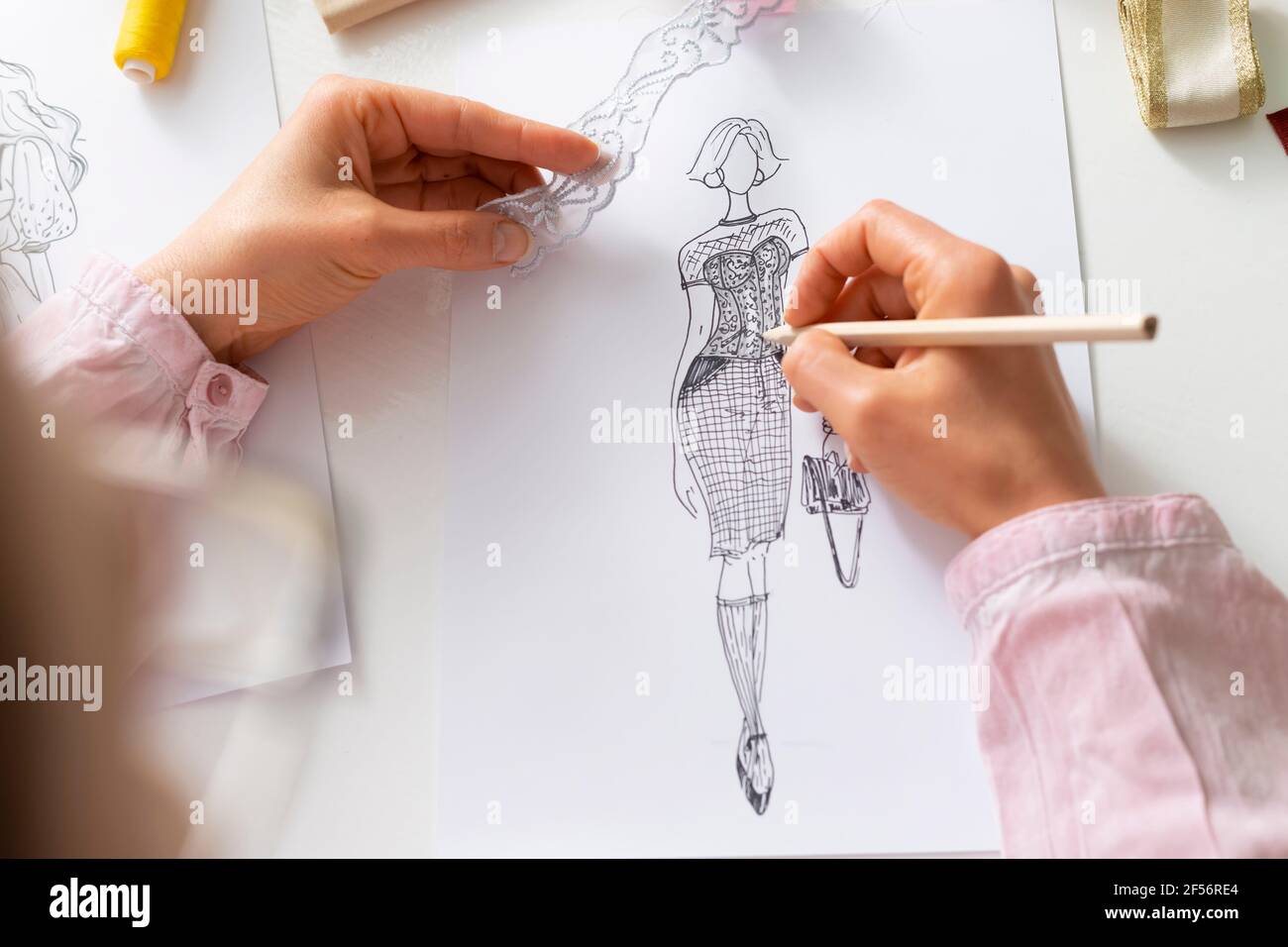 El diseñador dibuja bocetos de ropa femenina de moda en el papel en el  lugar de trabajo Fotografía de stock - Alamy