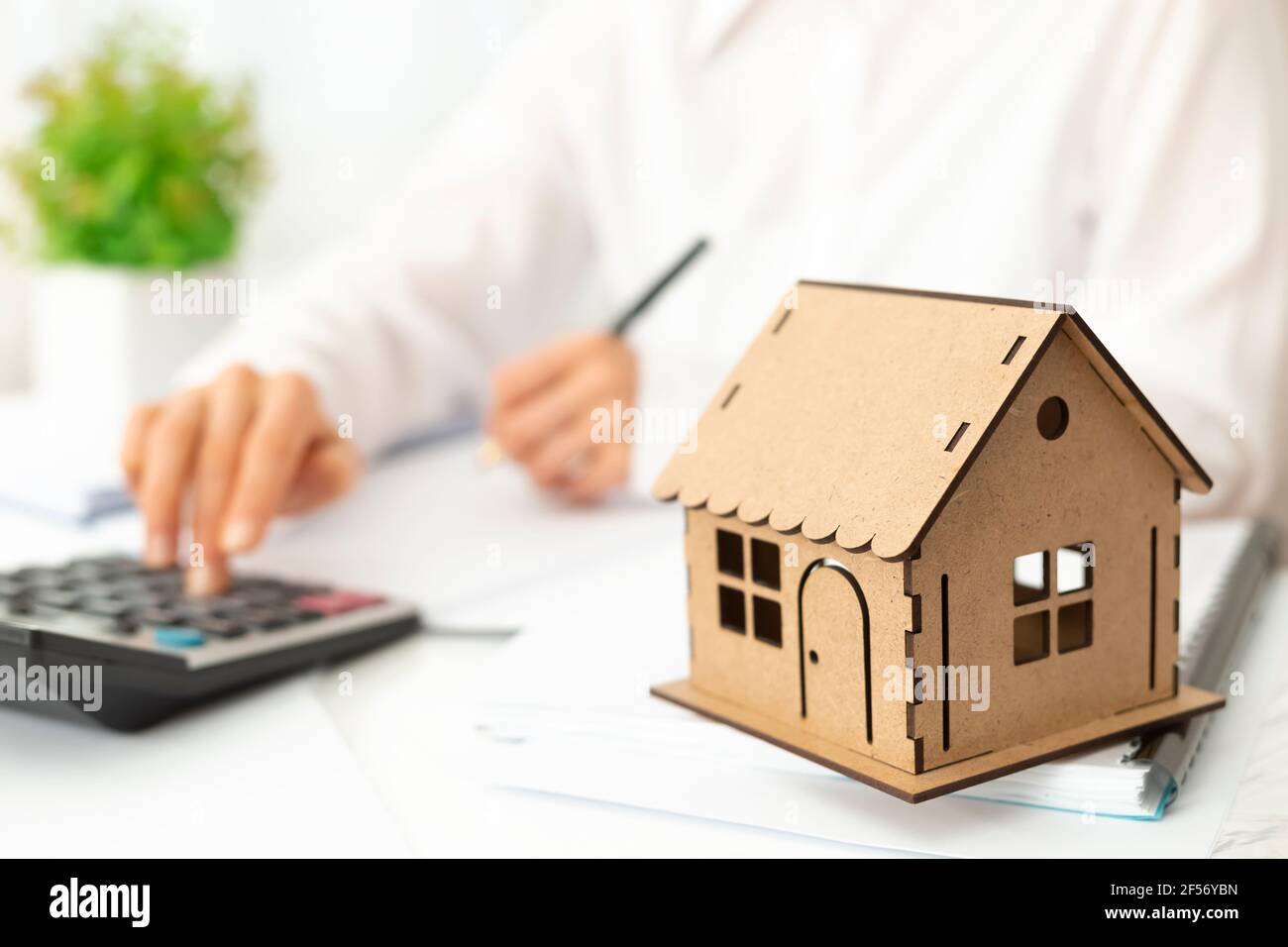 El agente inmobiliario cuenta con una calculadora y la escribe en el documento. Un agente de bienes raíces está trabajando en su escritorio. Foto de stock