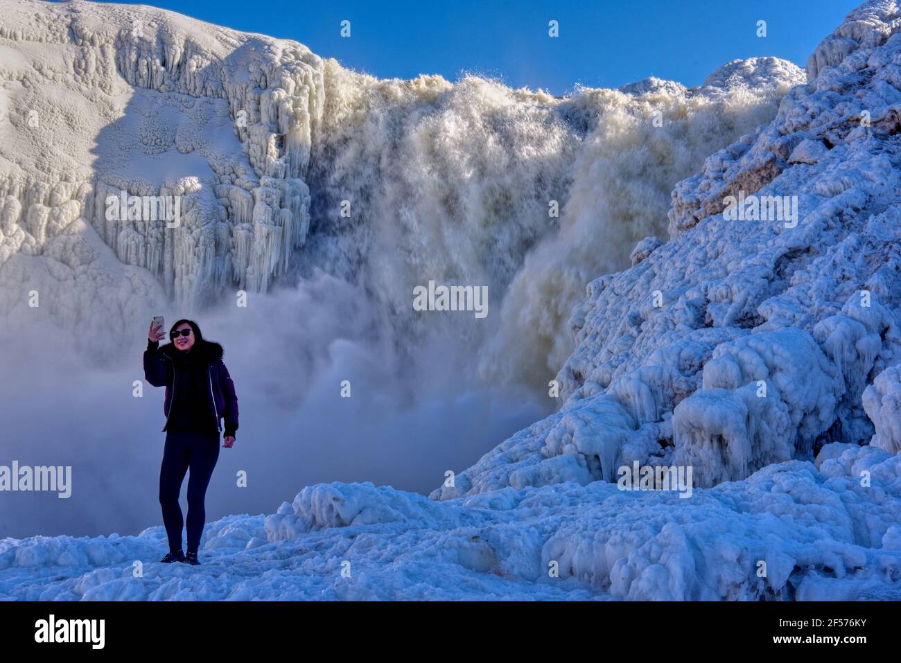 Una mujer asiática solitaria tomando un selfie en los Chutes de la Chaudière congelados en la ciudad de Quebec, Canadá Foto de stock