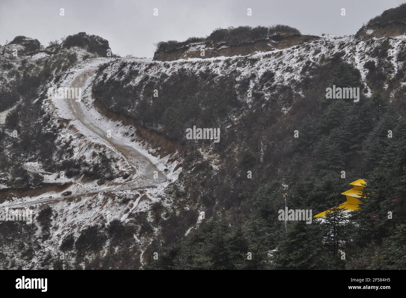 Templo nepalí con techo amarillo en la cima de la colina, camino en espiral cubierto de nieve, camino que conduce al templo Foto de stock
