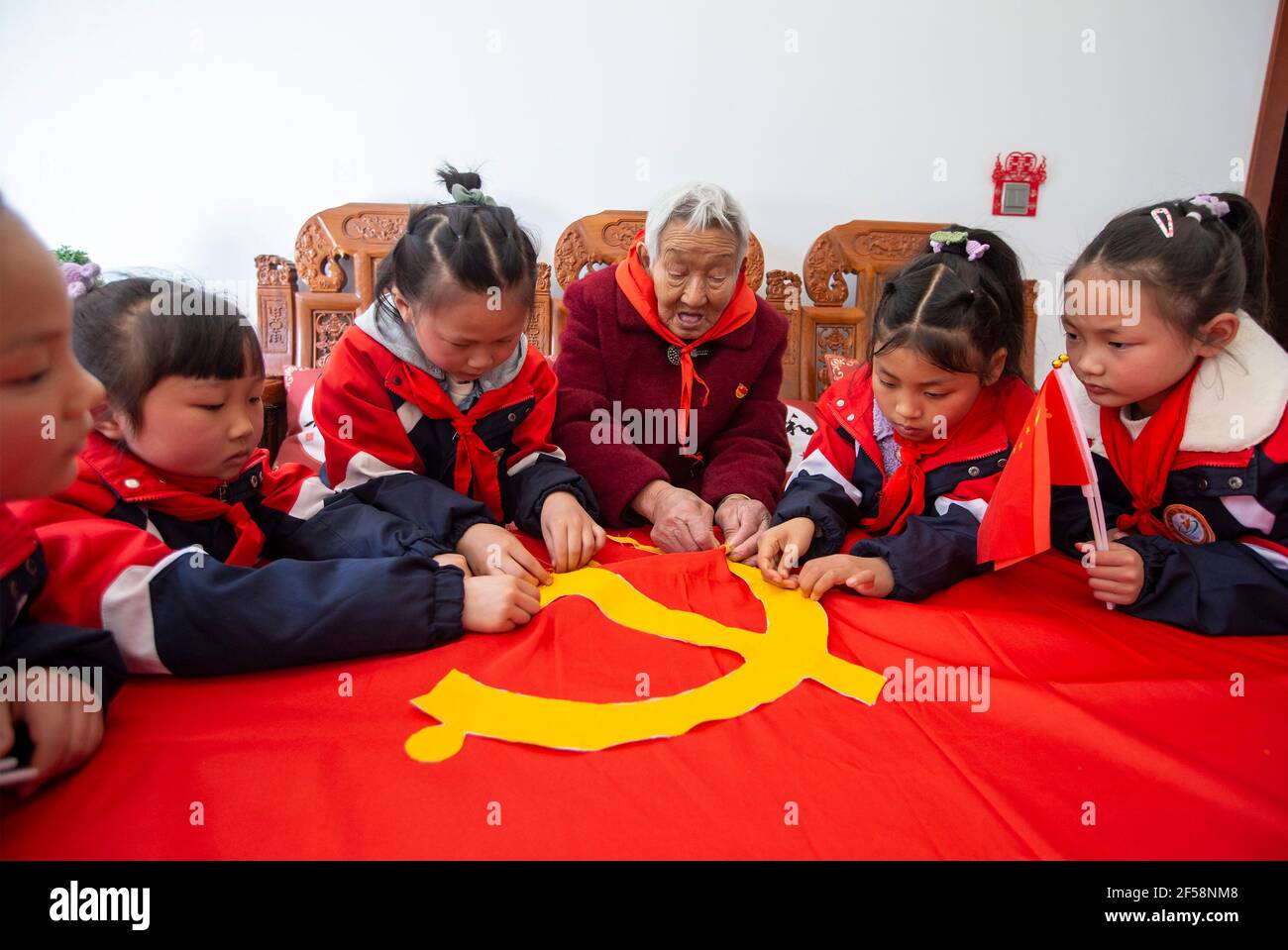 HAI'AN, CHINA - 25 DE MARZO de 2021 - estudiantes de primaria enbroider la bandera del Partido con Gu Guangying, un veterano miembro del Partido antes de la fundación de la República Popular de China, en Hai 'an, provincia de Jiangsu, China Oriental, 25 de marzo de 2021. (Foto de Zhai Huiyong / Costfoto/Sipa USA) crédito: SIPA USA/Alamy Live News Foto de stock