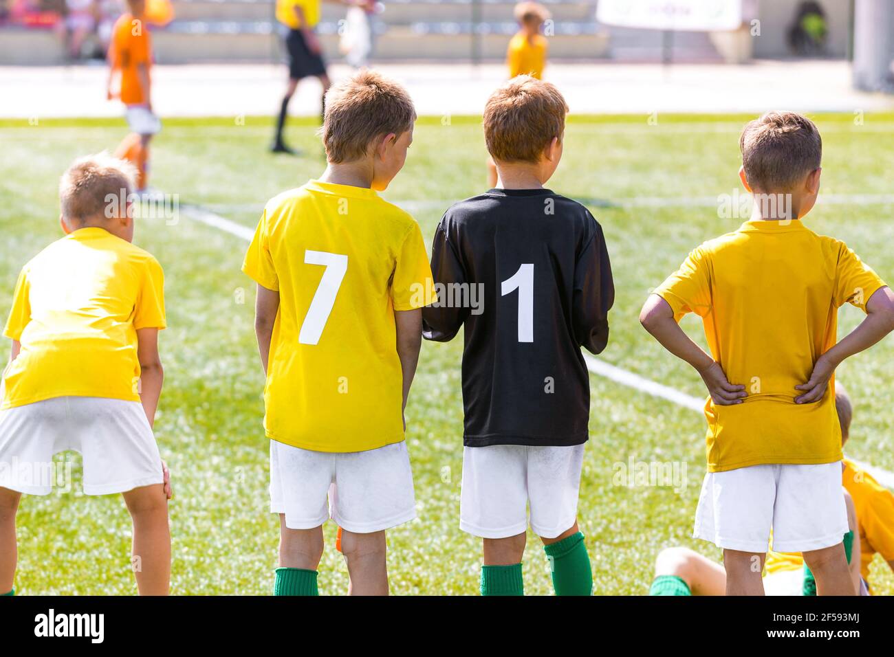 en camisetas de fútbol amarillas números de jugador en la espalda. Equipo de fútbol pie en Sideline. Grupo de niños jóvenes en el equipo de deportes escolares. Fútbol para