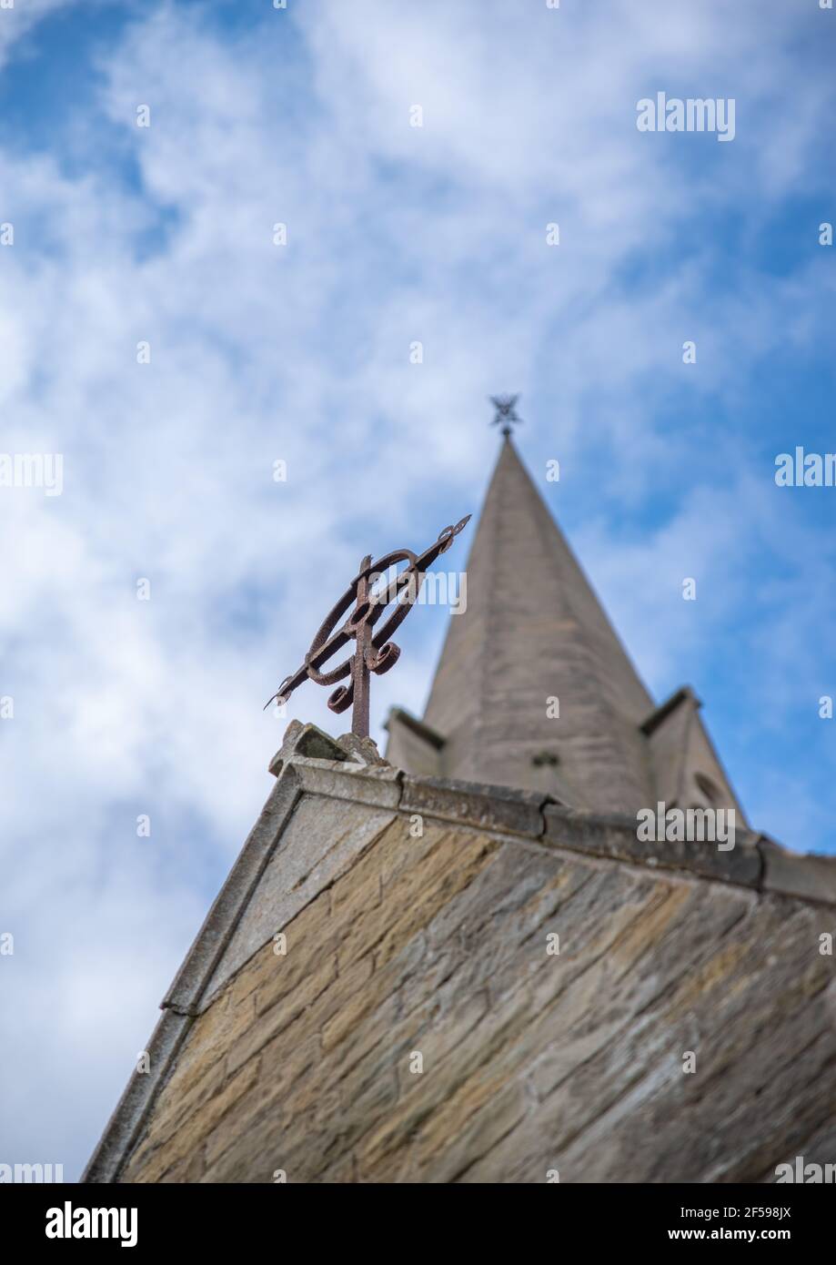 Símbolo de cruz desde abajo mirando a un campanario de la iglesia con un fondo azul cielo nublado. Foto de stock