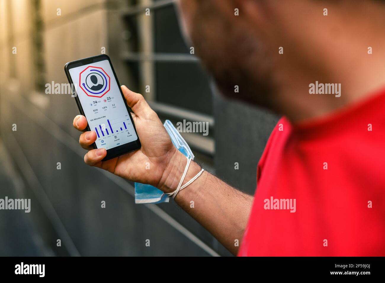 Primer plano de manos masculinas con la aplicación de ejercicio en el smartphone. Hombre descansando después de correr leyendo resultados de carrera. Hombre corriendo con teléfono móvil conectado a un sm Foto de stock