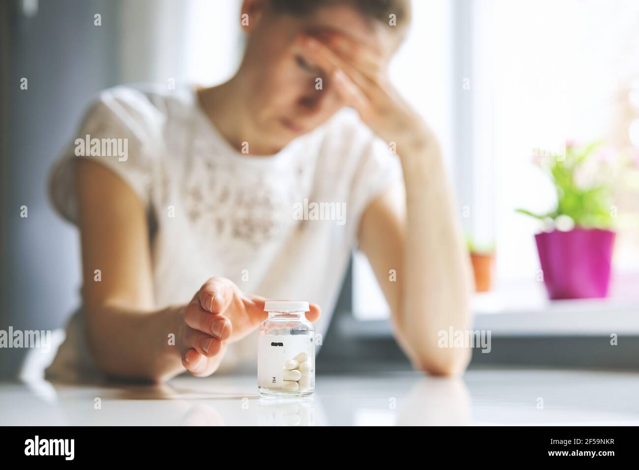 mujer con dolor de cabeza que alcanza para las píldoras del dolor. migraña, cefalalgia y el concepto del estrés Foto de stock