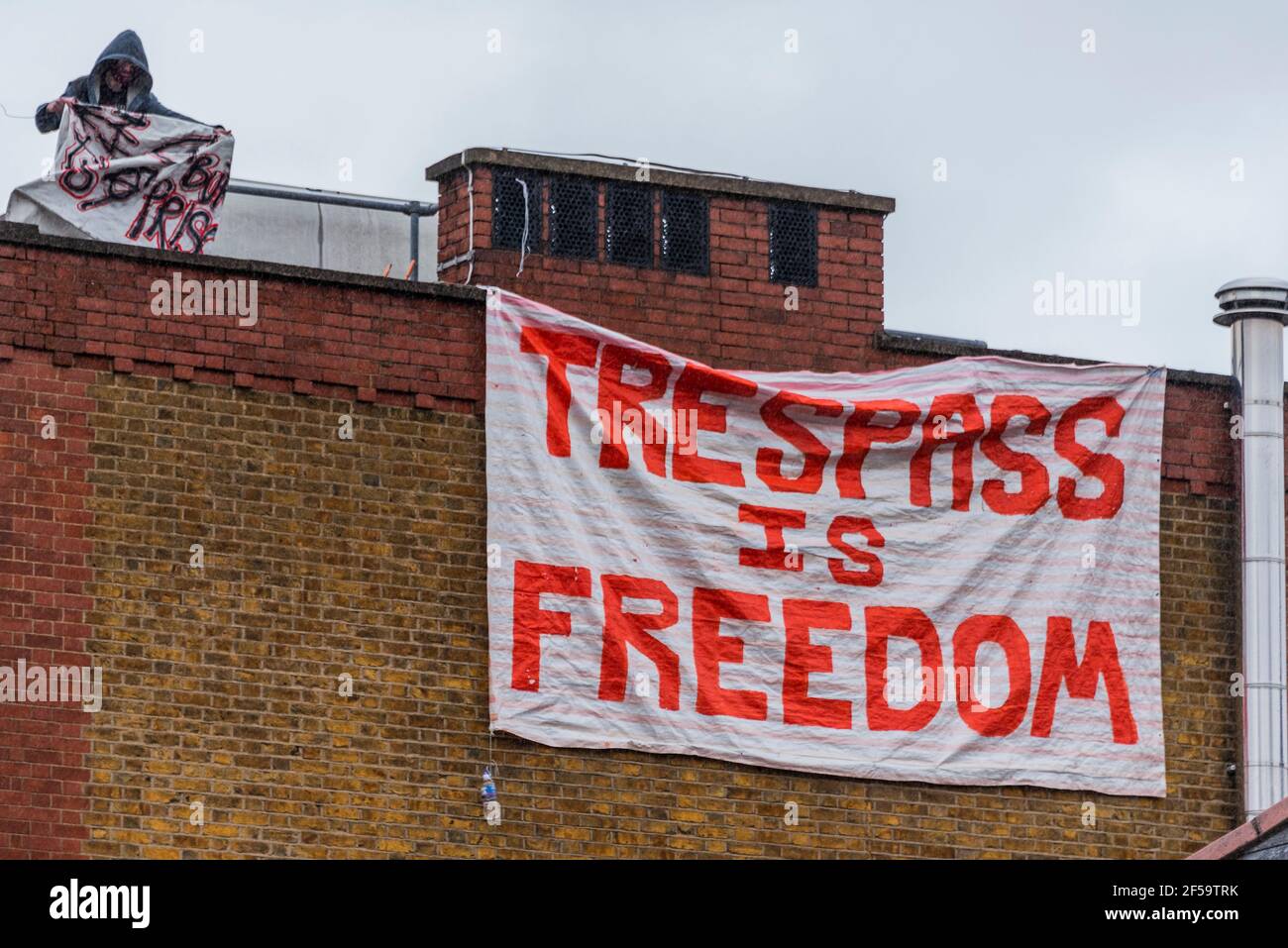 Londres, Reino Unido. 25 de marzo de 2021. Una gran resaca es la bandera de la libertad se cuelga del techo y más tarde se cae - los ocupantes ilegales y activistas han ocupado la antigua comisaría de policía común de Clapham para exigir "la retirada de la policía, el crimen, Sentencia y tribunales Bill y el fin del femicidio recientemente destacado por el asesinato de Sarah Everard por un agente de policía se reunió". Habría sido la estación más cercana a donde Sarah fue vista por última vez. Aunque el proyecto de ley se ha pospuesto actualmente, quieren asegurarse de que no se apruebe y también están tratando de destacar la Sección 4 del proyecto de ley, que critica Foto de stock