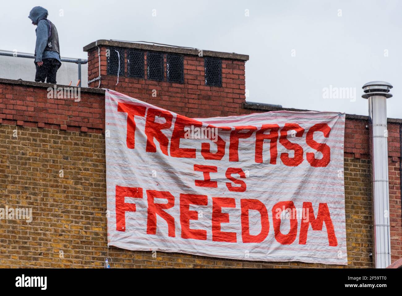 Londres, Reino Unido. 25 de marzo de 2021. Una gran resaca es la bandera de la libertad se cuelga del techo y más tarde se cae - los ocupantes ilegales y activistas han ocupado la antigua comisaría de policía común de Clapham para exigir "la retirada de la policía, el crimen, Sentencia y tribunales Bill y el fin del femicidio recientemente destacado por el asesinato de Sarah Everard por un agente de policía se reunió". Habría sido la estación más cercana a donde Sarah fue vista por última vez. Aunque el proyecto de ley se ha pospuesto actualmente, quieren asegurarse de que no se apruebe y también están tratando de destacar la Sección 4 del proyecto de ley, que critica Foto de stock