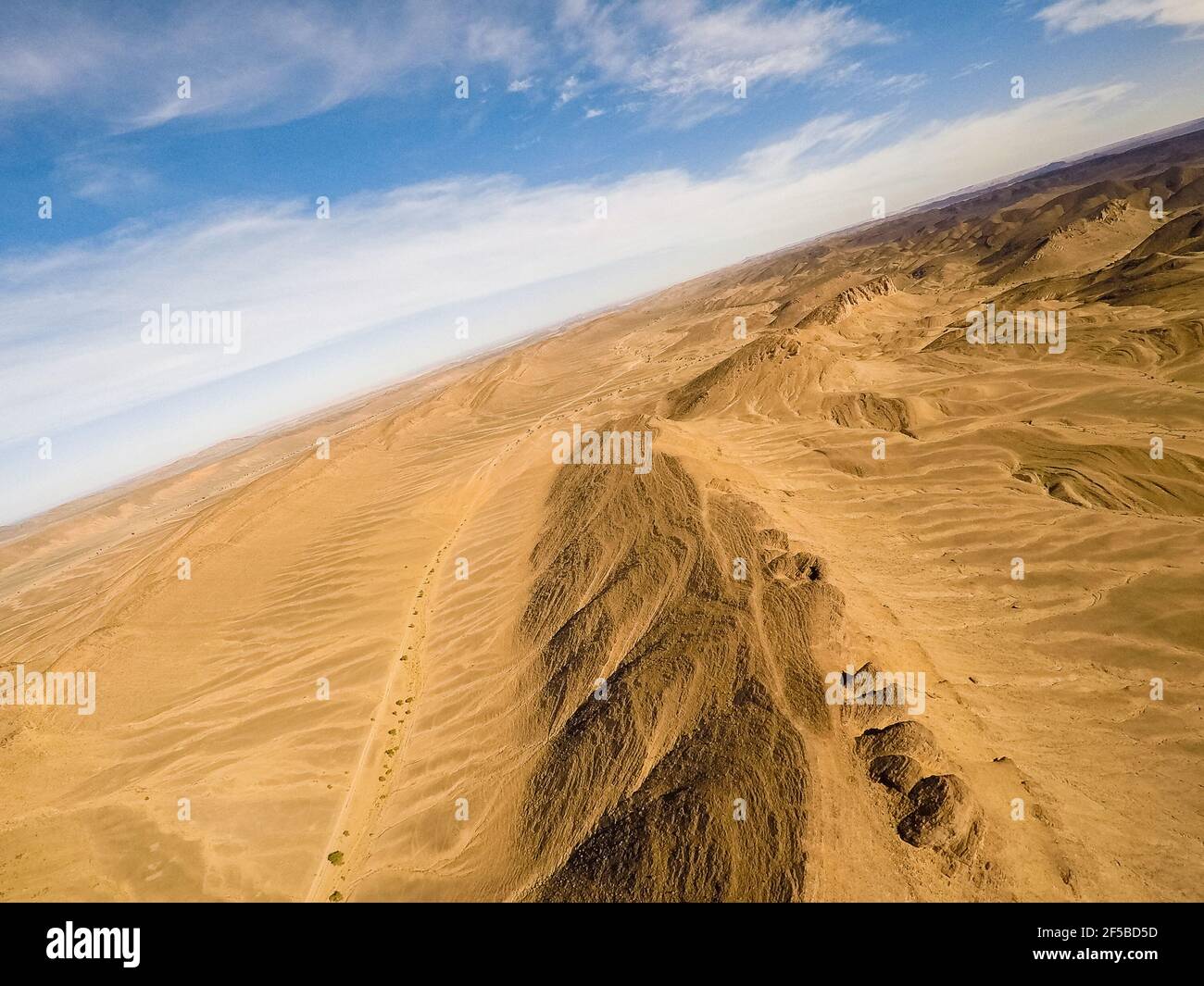 Drone POV fotografía aérea con horizonte sesgado de una montaña ridge en la luz del día brillante en el desierto del sahara Foto de stock