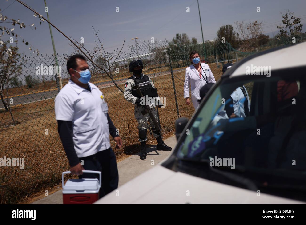 Los miembros de la Guardia Nacional vigilan mientras la gente espera recibir la vacuna China Sinovac Biotech contra la enfermedad del coronavirus (COVID-19) durante el programa de vacunación masiva para las personas mayores en un punto de vacunación en la Ciudad de México, México 25 de marzo de 2021. REUTERS/Edgard Garrido Foto de stock