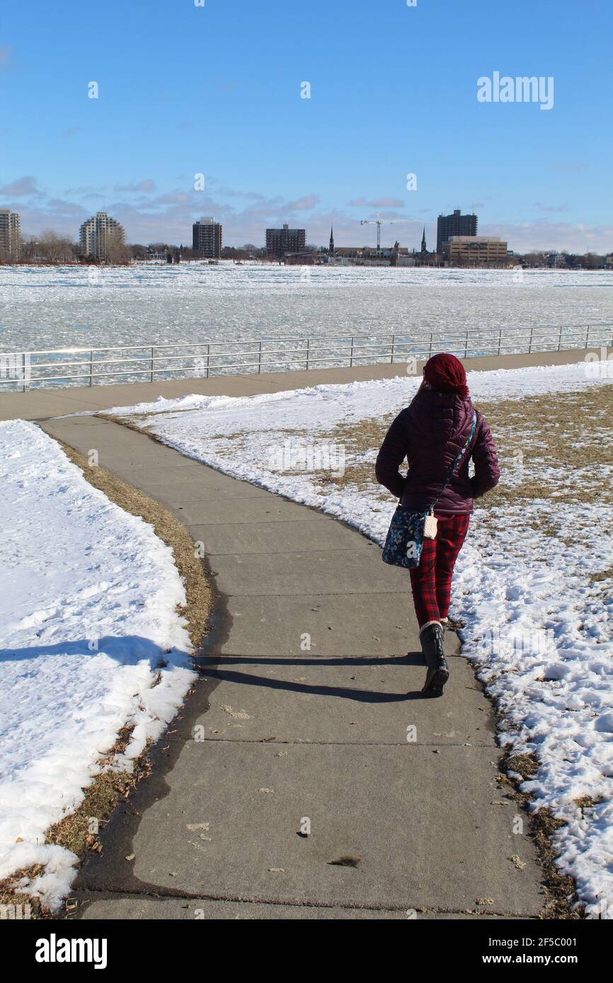 Mujer caminando hacia el camino del río St. Clair en Port Huron, Michigan con Canadá en el fondo Foto de stock