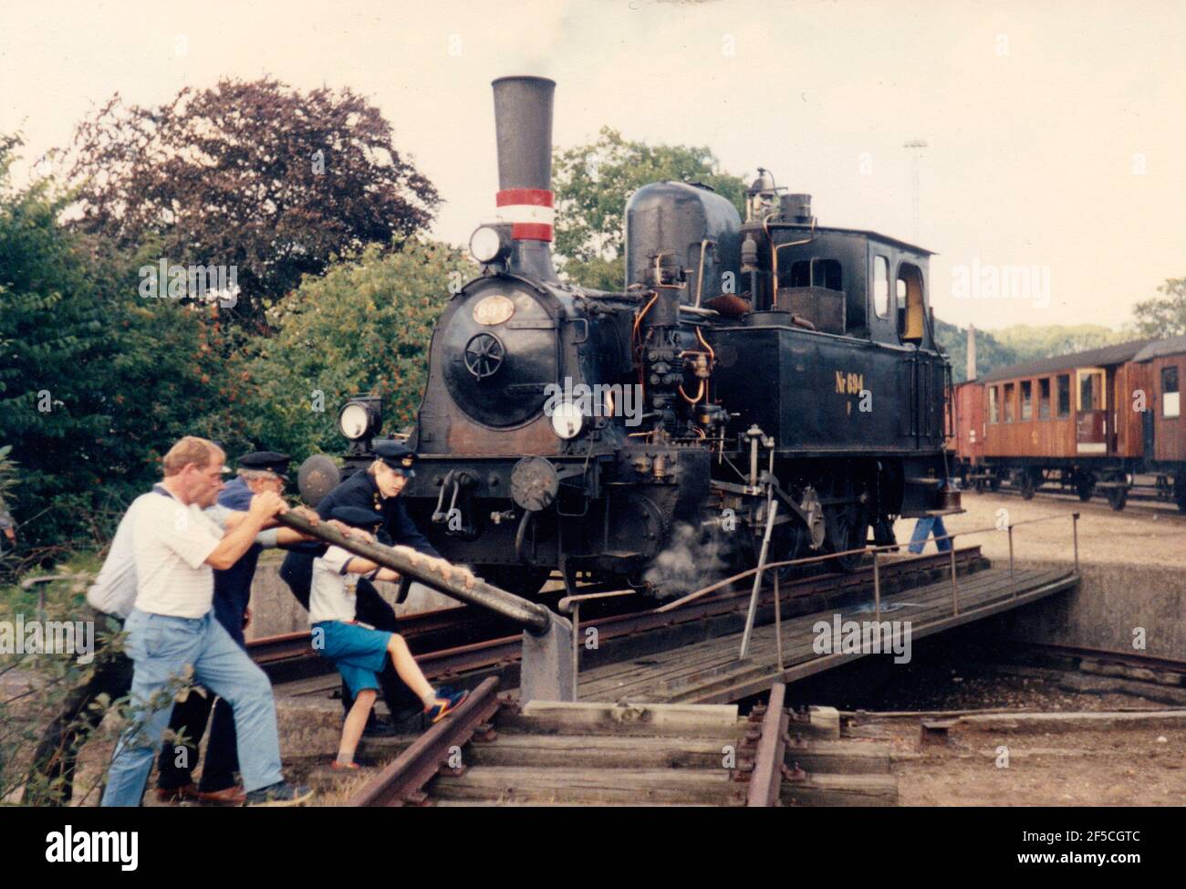 Vejle, Dinamarca - alrededor del año 1985: Los entusiastas del ferrocarril de la vendimia da vuelta a la locomotora de vapor F694 en la turnable pequeña. Foto de stock