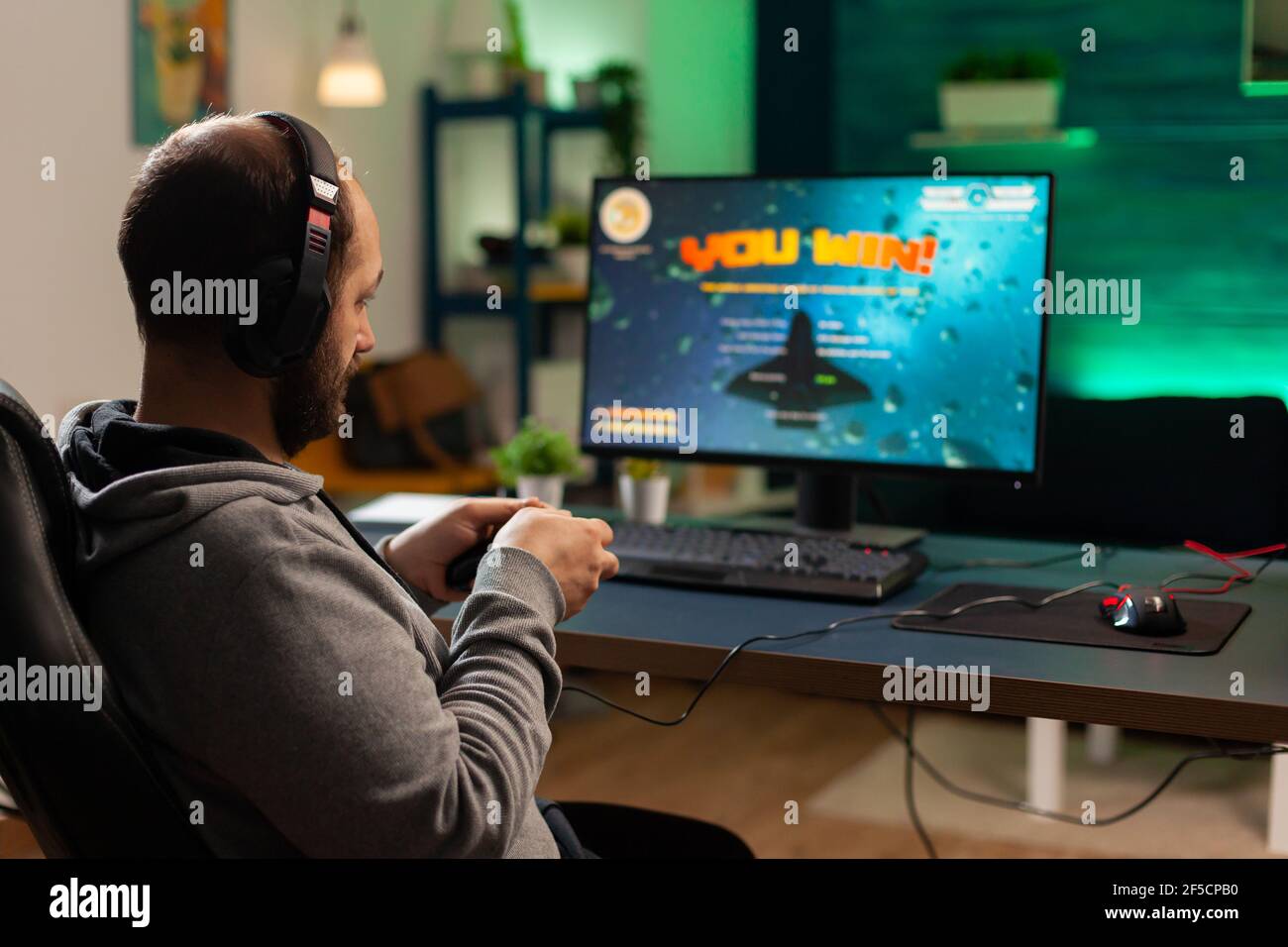 Foto de fondo de un jugador profesional jugando juego de disparos en línea en el ordenador utilizando mando inalámbrico. El jugador competitivo que torneo de videojuegos utiliza equipo profesional