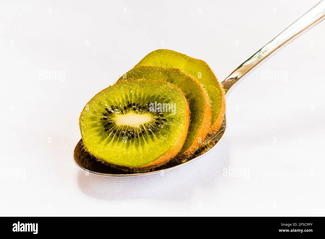 Primer plano de rodajas de kiwi en una cuchara de plata sobre un mantel blanco, Londres, Reino Unido Foto de stock
