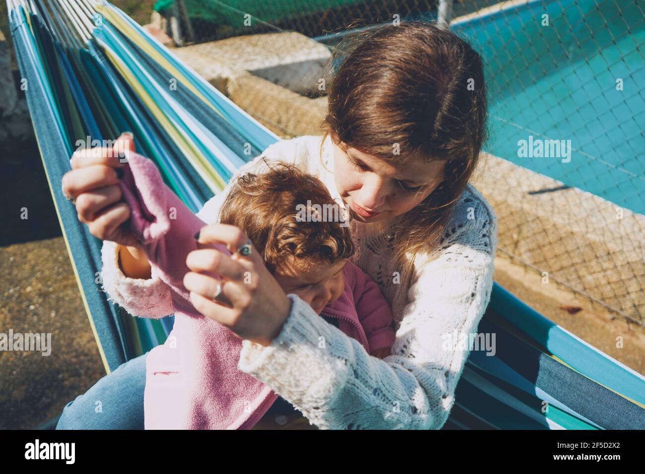 Mujer joven cuidando a su bebé sentado en una hamaca Foto de stock