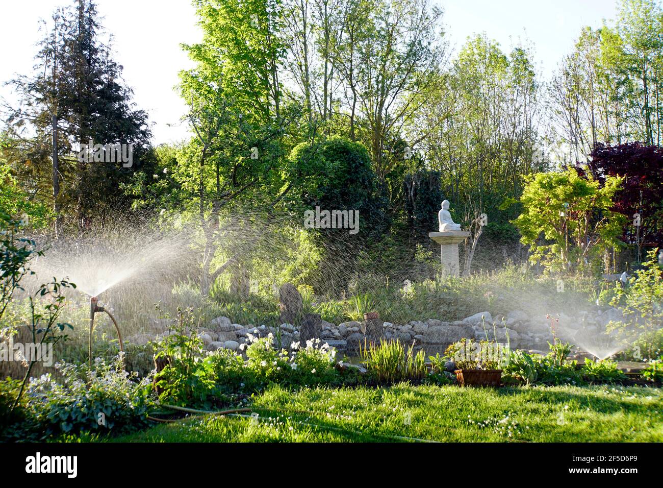 Riego artificial de césped y flores en el jardín, Alemania Foto de stock