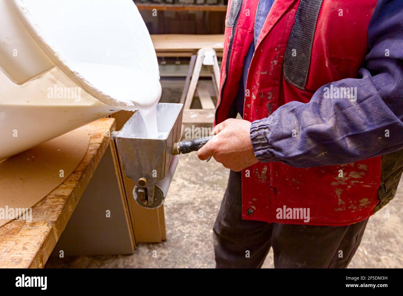 Carpenter vierte el pegamento del cubo de plástico en la herramienta del  rodillo de mano para aplicar el adhesivo en la superficie de madera que  necesita ser pegado Fotografía de stock -