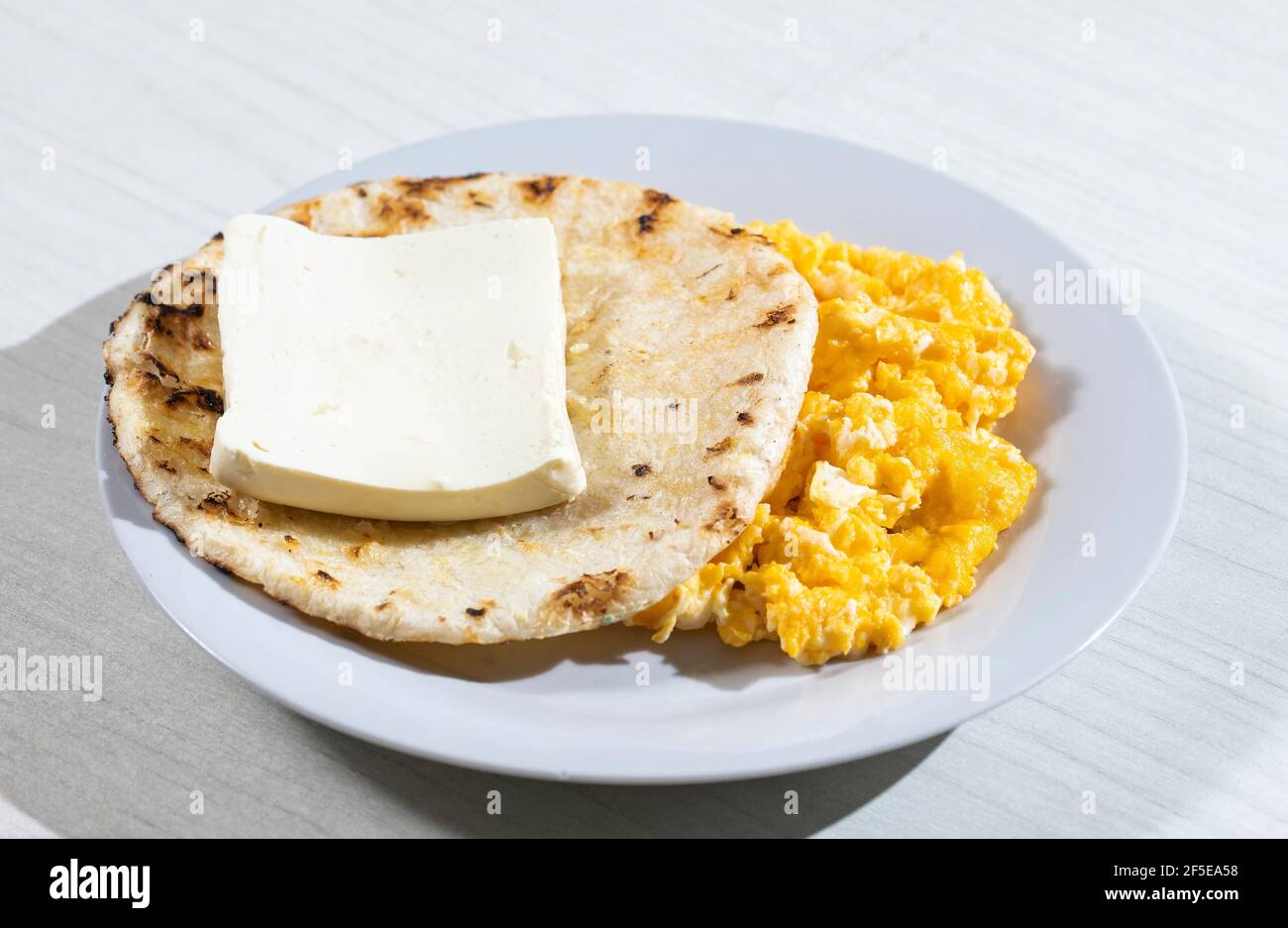 Arepa de desayuno, queso y huevo revuelto, plato tradicional colombiano