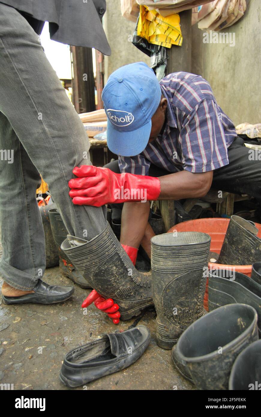 Hombre joven que alquila botas de lluvia a su cliente durante la temporada  de lluvias en el mercado Mile 12, Lagos, Nigeria Fotografía de stock - Alamy