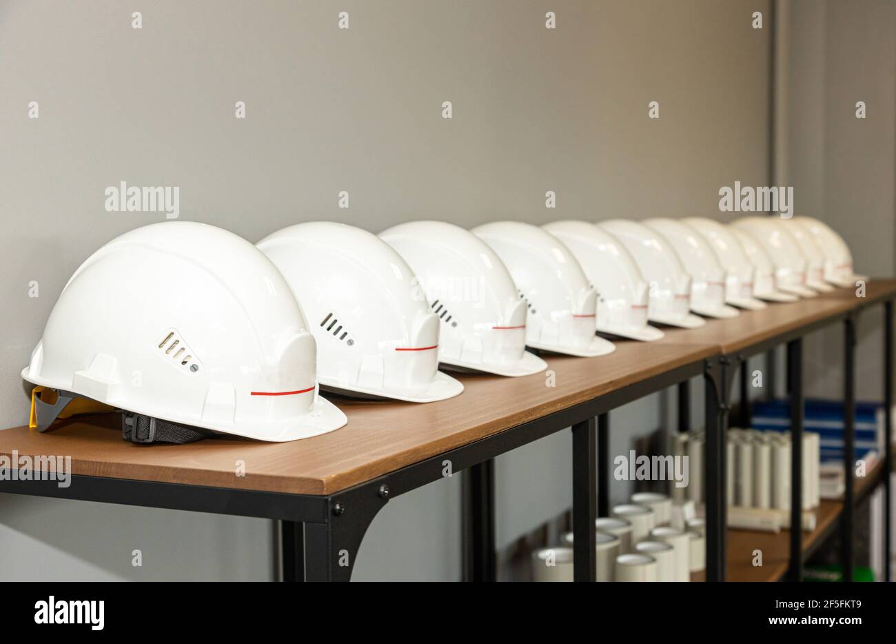 Los cascos blancos de la ingeniería de protección se encuentran en una fila  en un estante en una fábrica, la seguridad industrial y la protección de la  mano de obra Fotografía de
