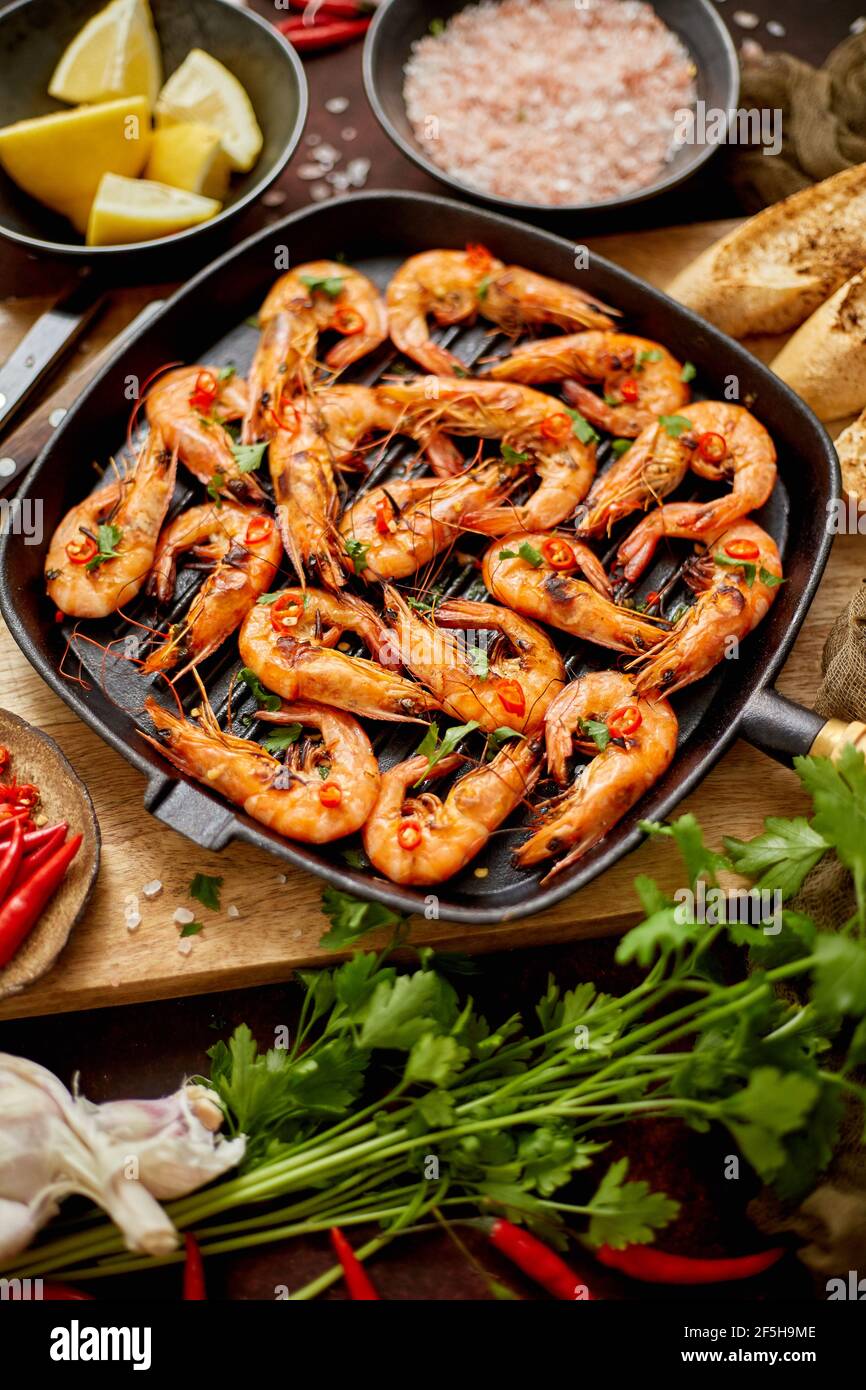 Gambas de tigre asadas en una sartén de hierro con pernera fresca, limón, Chile y pan Foto de stock