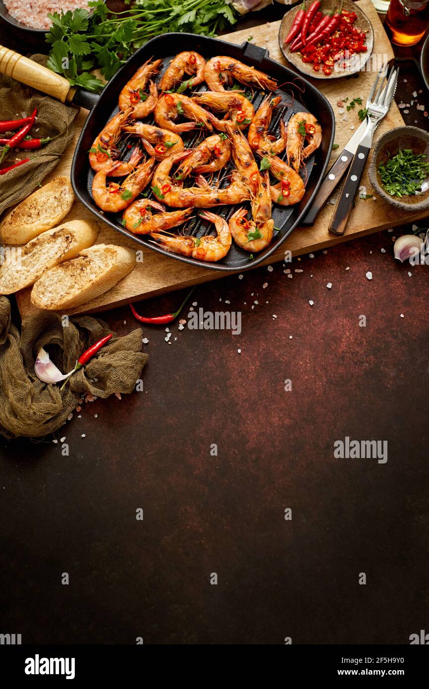 Gambas a la parrilla en una sartén de hierro fundido con limón fresco, perejil, Chile, ajo y salsa de vino blanco Foto de stock