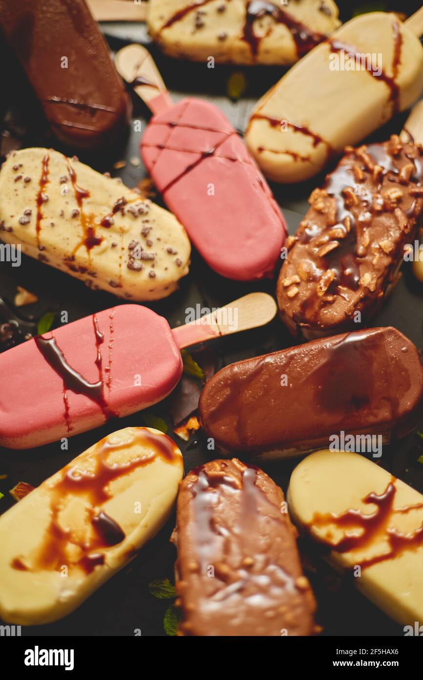 Helado en palo recubierto con varios esmaltes de chocolate y coberturas. Vista superior, plano Foto de stock
