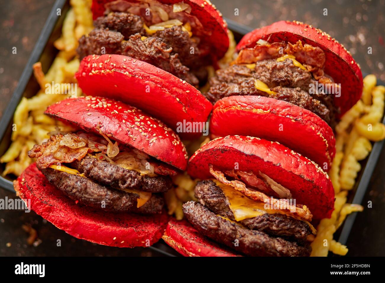 Juego de cuatro hamburguesas de queso de becon doble gigante caseras. Se sirve con patatas fritas a bordo de madera. Foto de stock