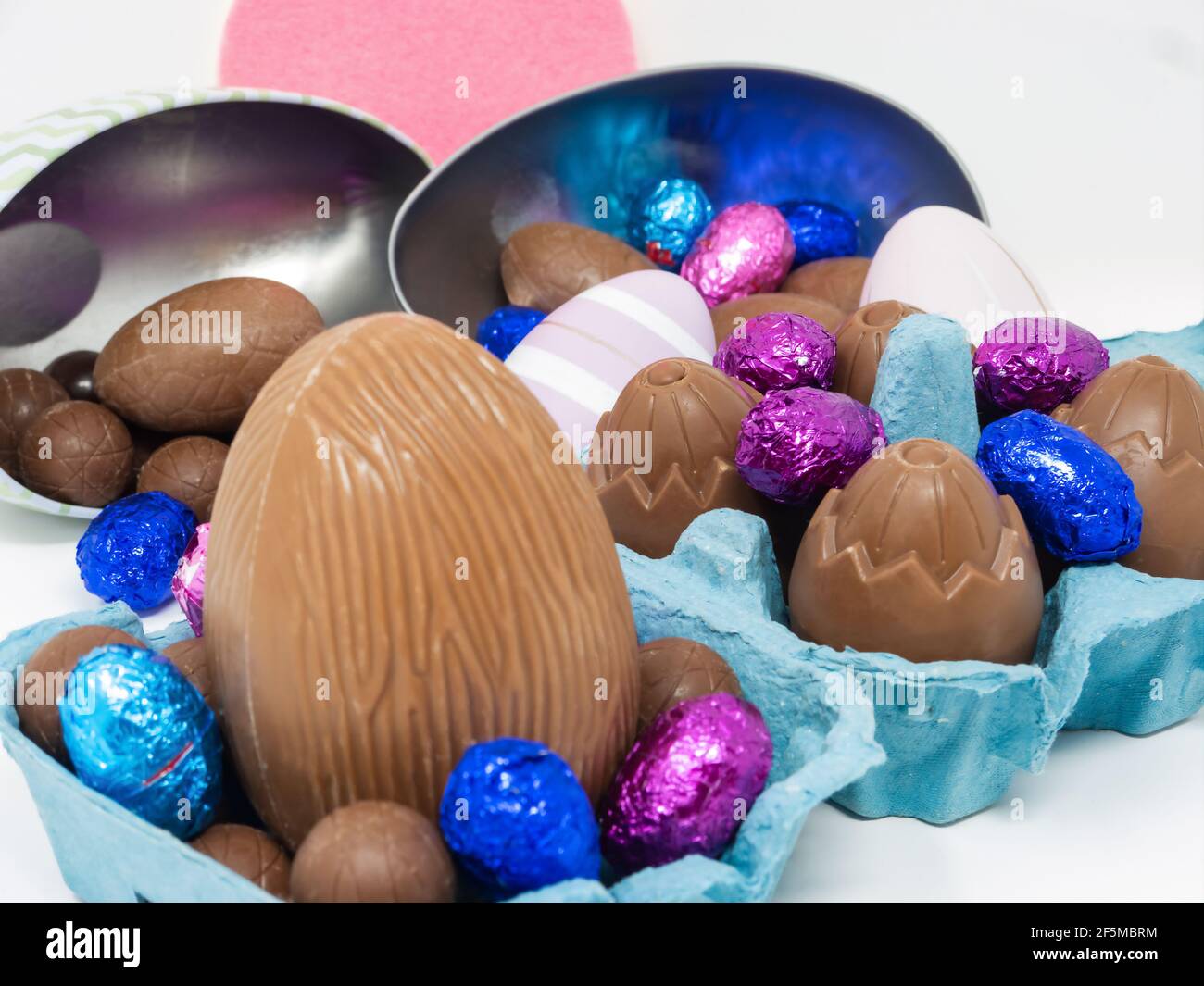 Un montón de huevos de Pascua de chocolate de diferentes tamaños en un cartón de huevo y en recipientes con forma de huevo Foto de stock