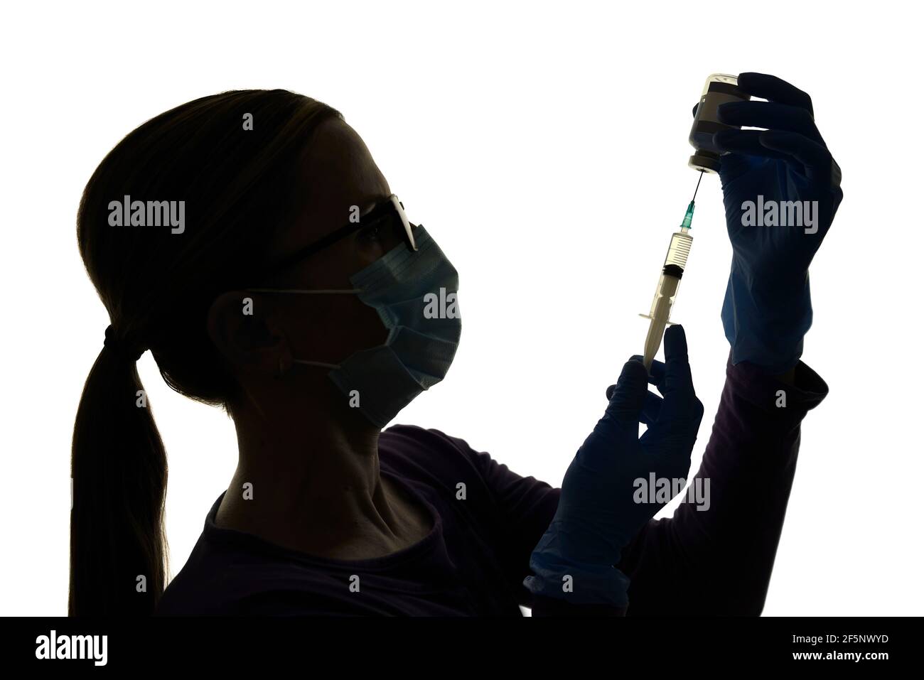 La enfermera se prepara para vacunar a un paciente con una vacuna contra el coronavirus, Silhoueted contra un fondo blanco Foto de stock