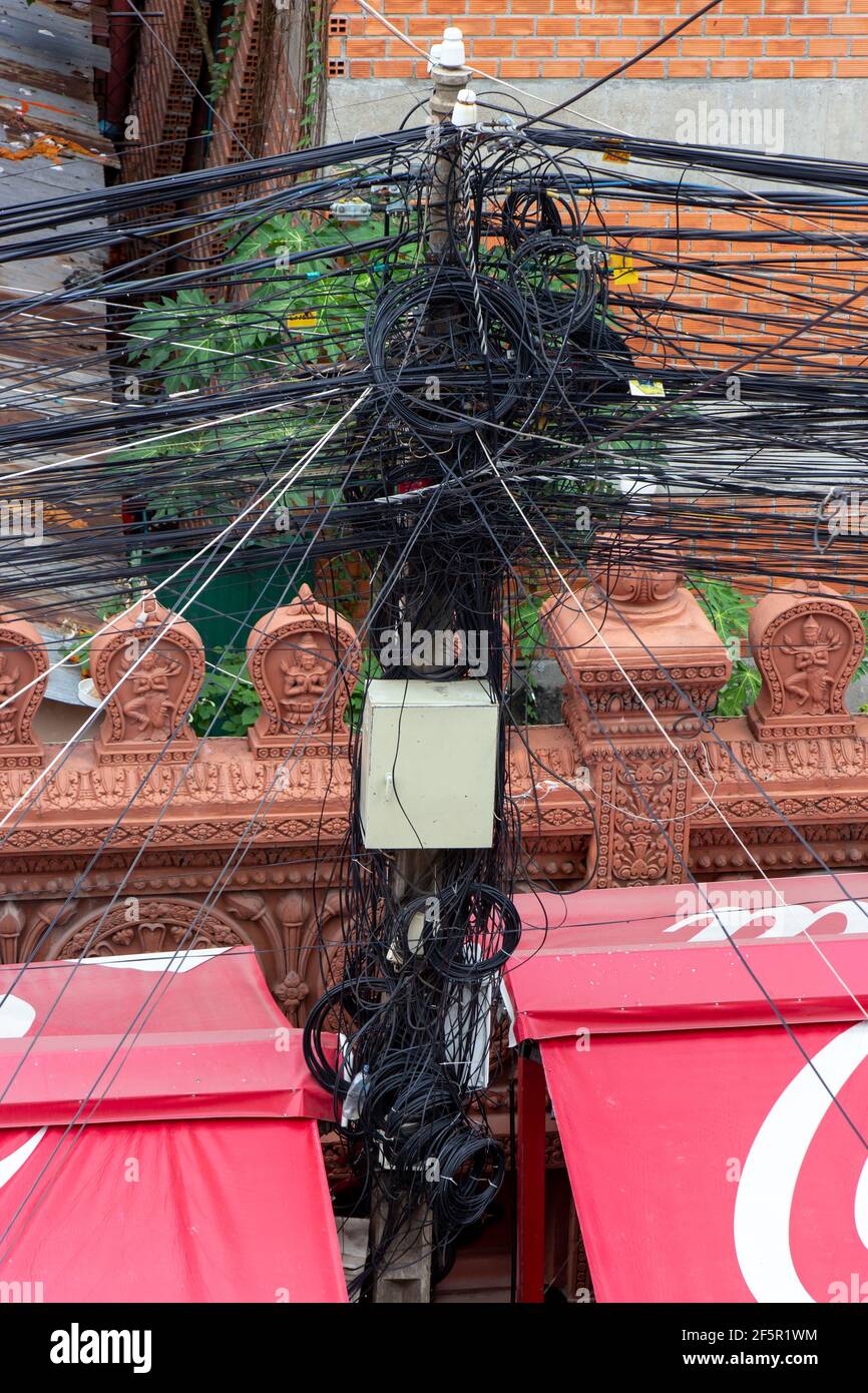 Cables conectados al mástil eléctrico. El caos de cables y cables en un polo eléctrico, Phnom Penh, Camboya. Foto de stock