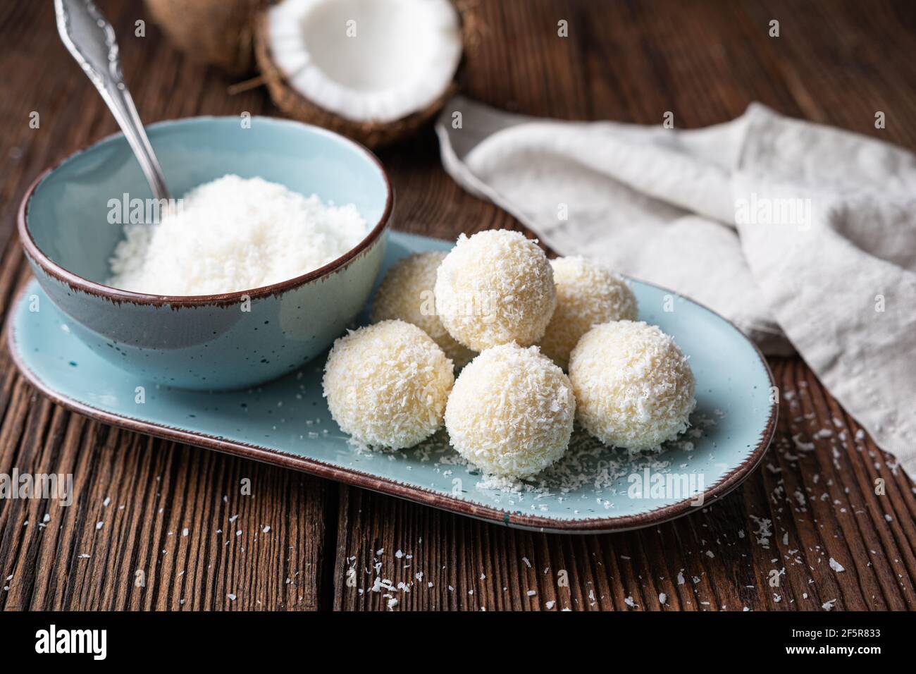 Delicioso caramelo sin hornear, trufas de chocolate blanco cubierto de coco rallado sobre fondo de madera rústica Foto de stock
