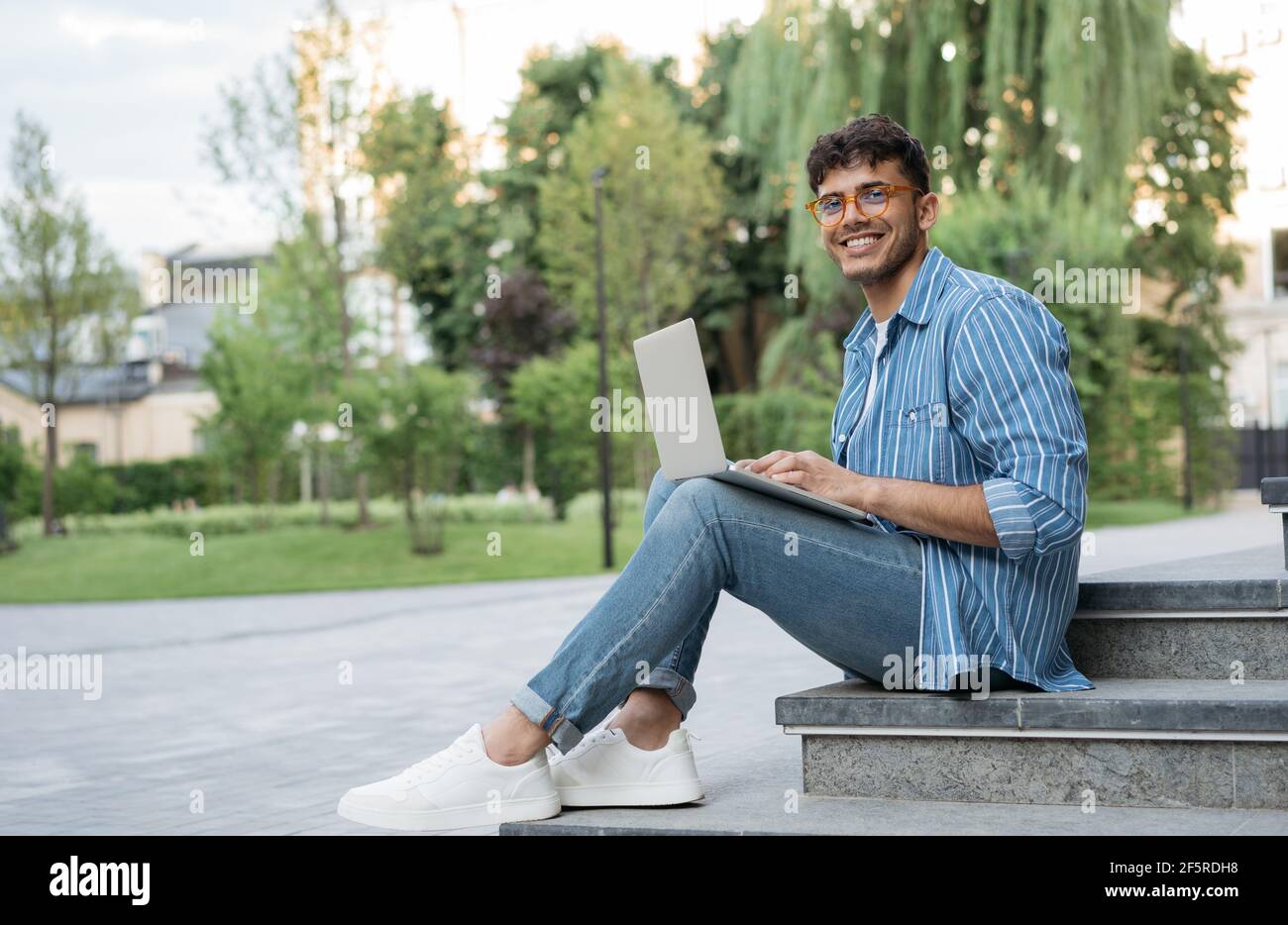 Sonriente programador indio usando computadora portátil, trabajando  proyecto independiente en línea, sentado en el parque. Estudiante asiático  estudiando, concepto de educación Fotografía de stock - Alamy