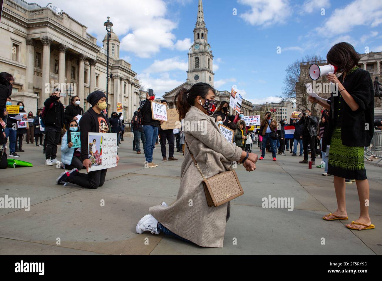 Un manifestante habla con sus colegas a través de un megáfono mientras se arrodillaba sosteniendo pancartas expresando su opinión durante una manifestación pacífica.manifestantes antigolpistas militares de Myanmar se reunieron en Trafalgar Square a medida que decenas más son asesinados en el país. La policía y los soldados militares de Myanmar (tatmadow) atacaron a los manifestantes con balas de goma, municiones vivas, gases lacrimógenos y bombas de aturdimiento en respuesta a los manifestantes contra el golpe militar el sábado en Myanmar, matando a más de 90 personas e hirieron a muchas otras. Al menos 300 personas han sido asesinadas en Myanmar desde el golpe de Estado del 1 de febrero, una situación de derechos humanos de la ONU Foto de stock