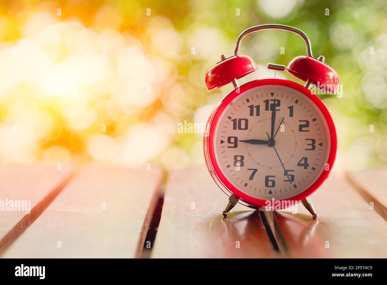 Reloj despertador clásico de 9 horas sobre mesa de madera con luz solar de  fondo verde Fotografía de stock - Alamy