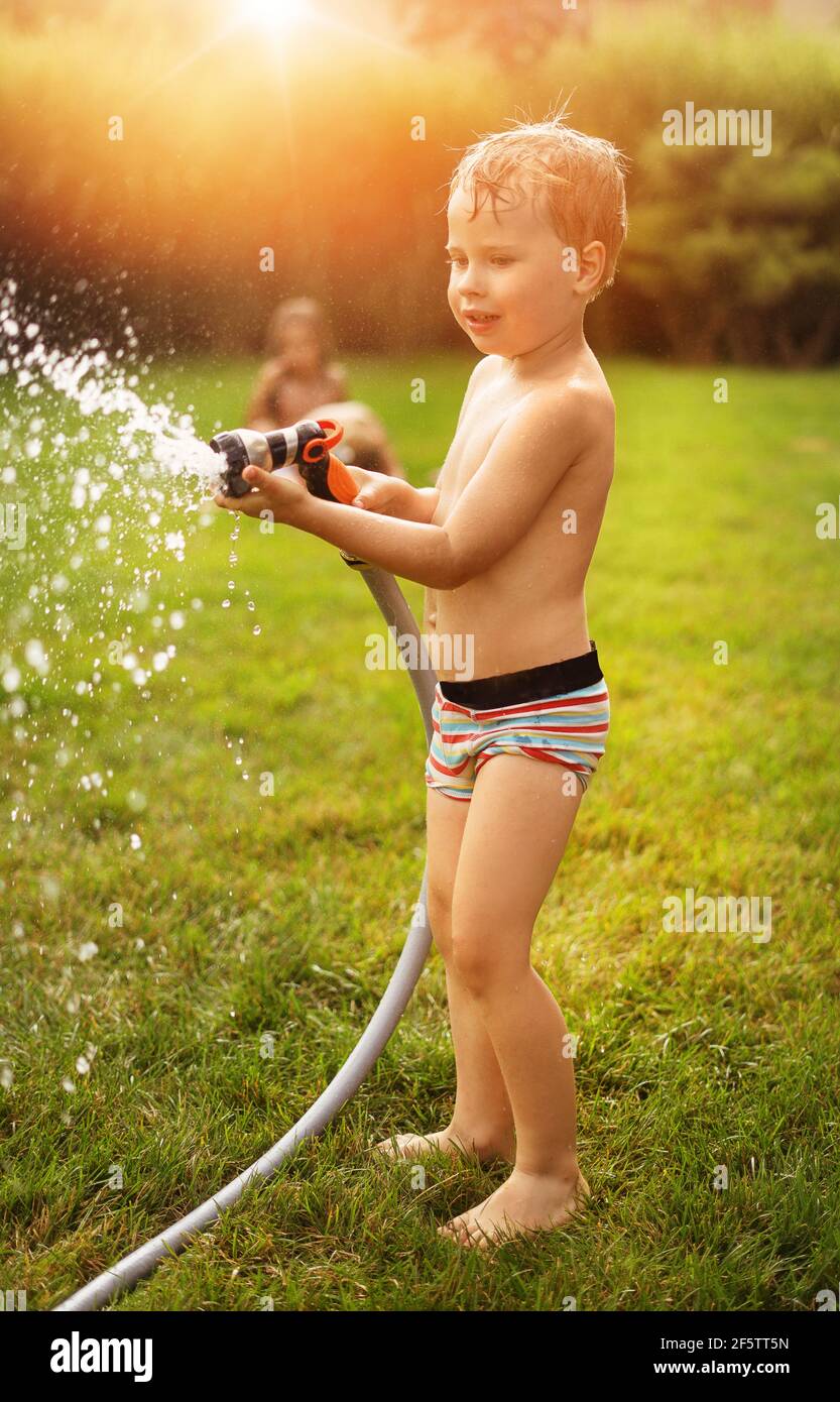 Niños alegres disfrutando de la ducha de verano en el jardín Foto de stock
