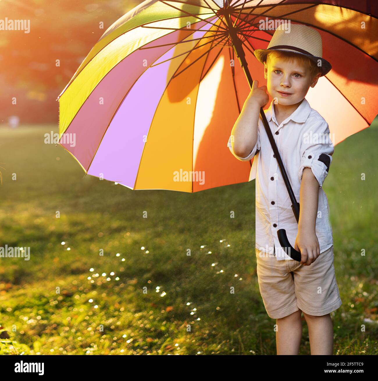 Lindo, pequeño, sosteniendo un paraguas enorme y colorido Foto de stock