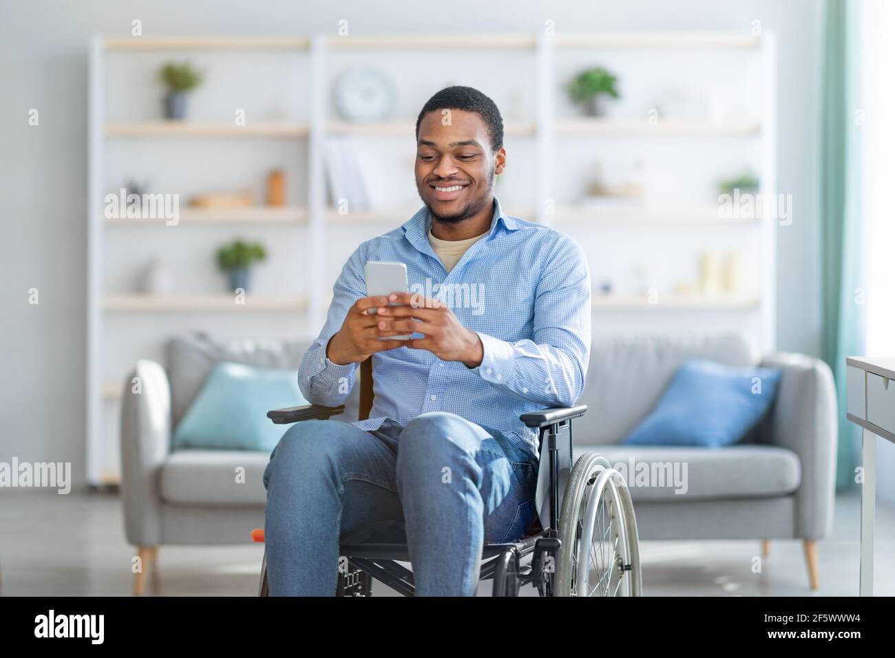 Hombre negro discapacitado en silla de ruedas usando un smartphone,  navegando por la web o viendo una película en casa Fotografía de stock -  Alamy